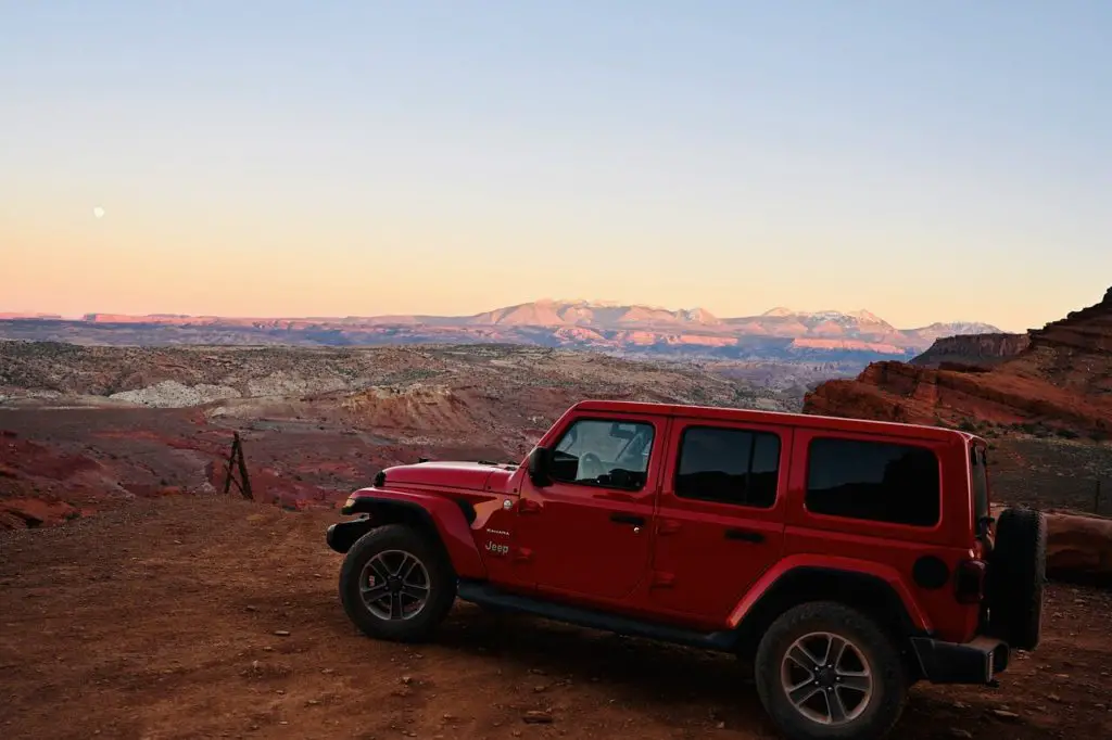red Jeep Wrangler parked on top of the mountain