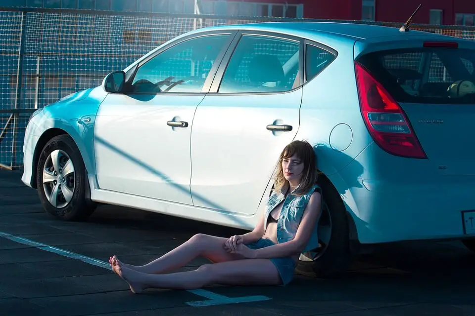 A woman comfortably seated by the her hatchback car, enjoying the outdoors