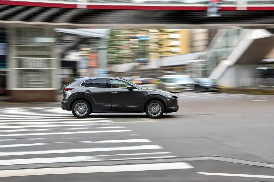 grey Mazda CX 30 side view driving in the city