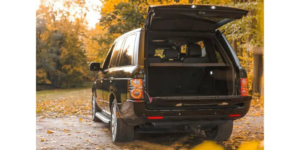 The image presents a captivating scene set in a picturesque park during autumn, featuring a sleek black Range Rover SUV as the focal point.